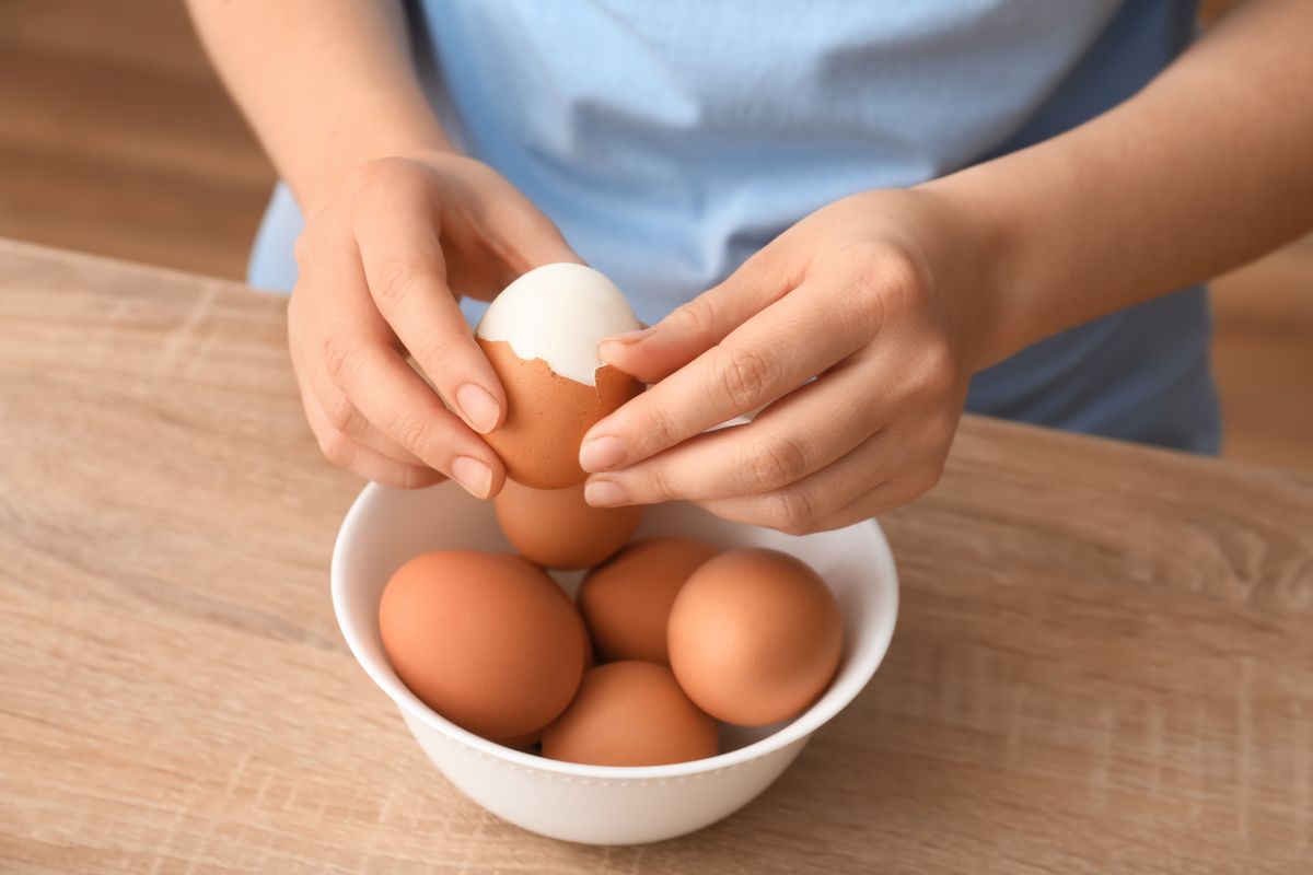 Woman,Peeling,Boiled,Egg,At,Wooden,Table,,Closeup
