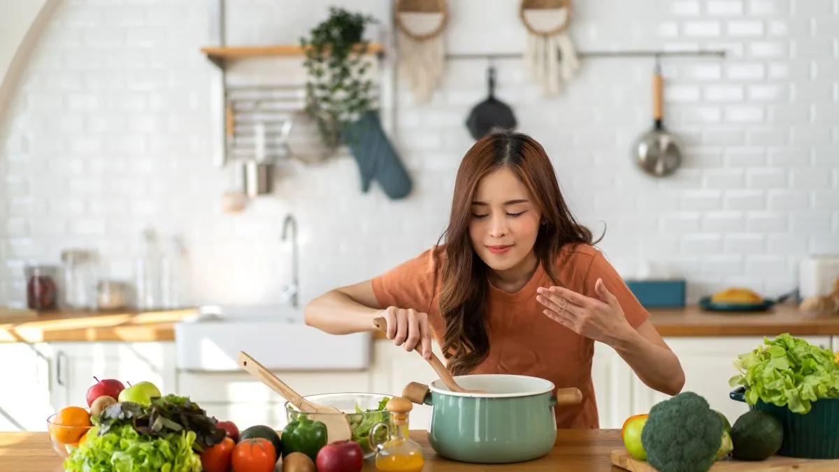 Young,Woman,Standing,Near,Stove,And,Cooking,,Housewife,,Meal,,Chef,