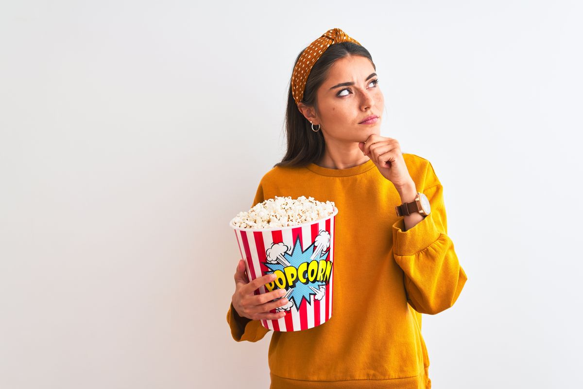 Young,Beautiful,Woman,Holding,Pack,Of,Popcorns,Standing,Over,Isolated