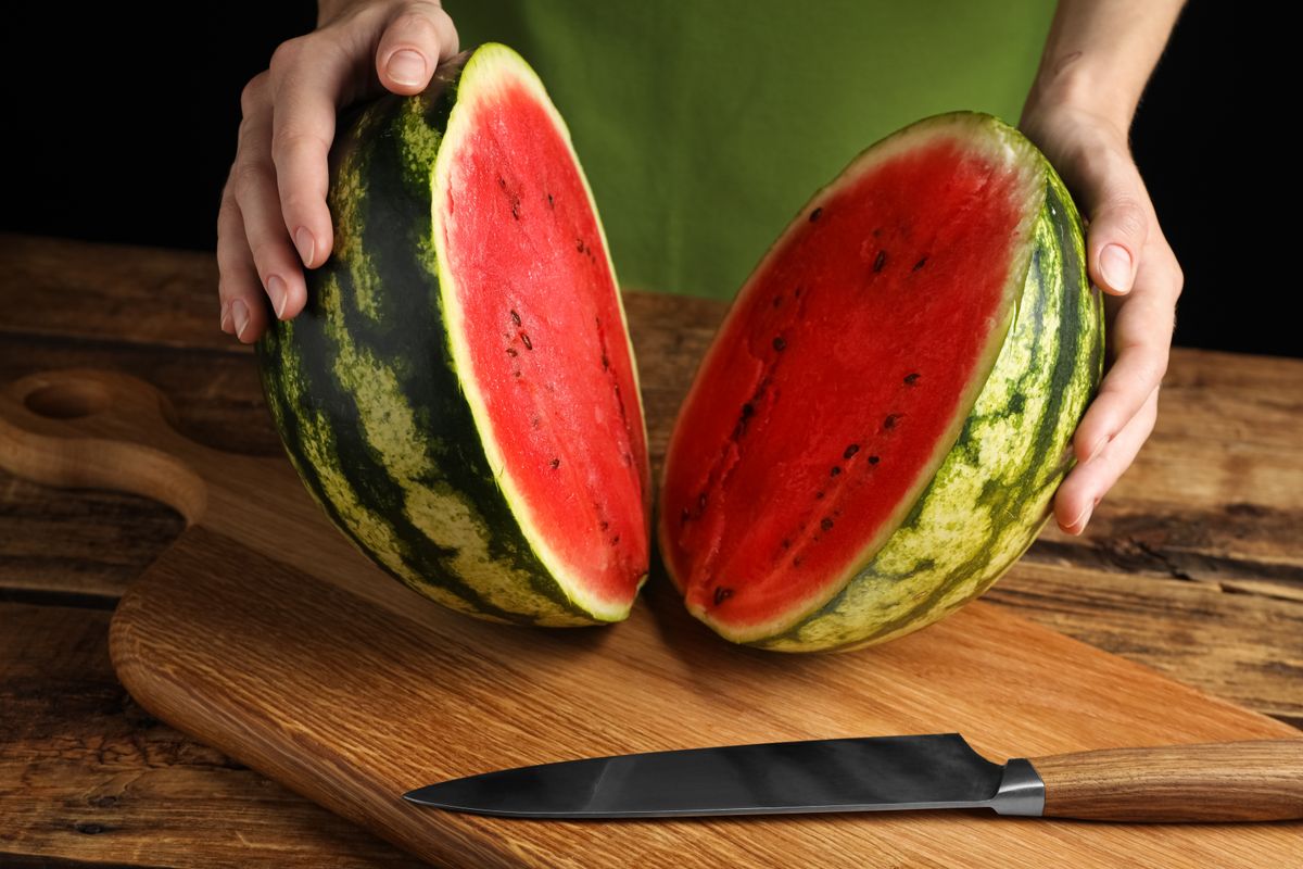 Woman,With,Delicious,Halved,Watermelon,At,Wooden,Table,Against,Black