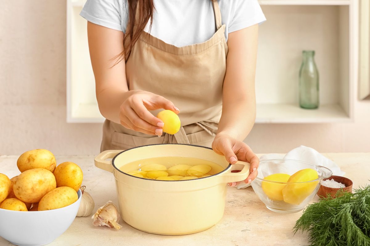Woman,Putting,Peeled,Potato,In,Pot,At,Table,In,Kitchen
