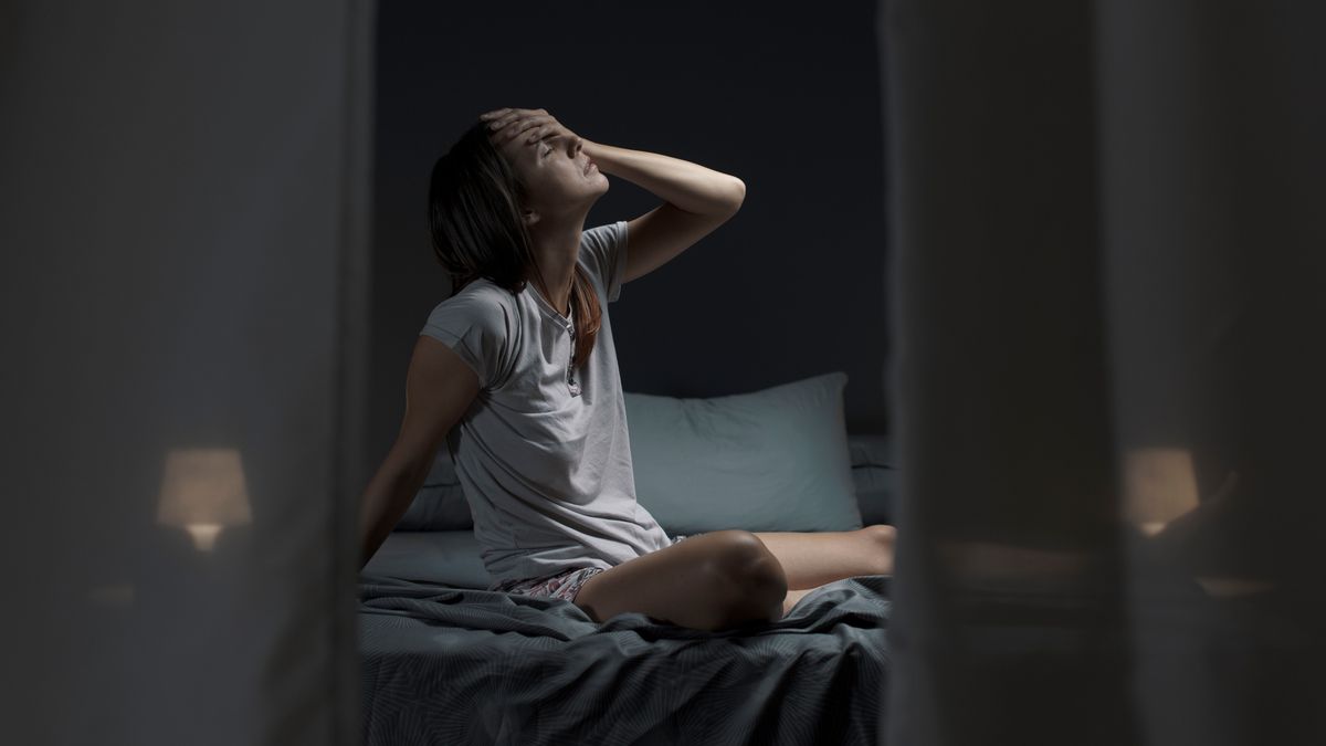 Tired,Woman,Sitting,In,Bed,At,Night,With,Open,Window,