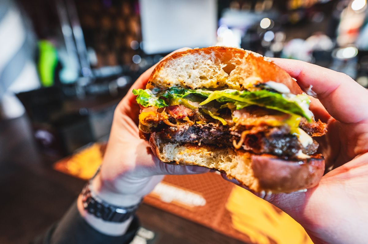 Close-up,Of,A,Hand,Holding,A,Half-eaten,Burger,With,Lettuce