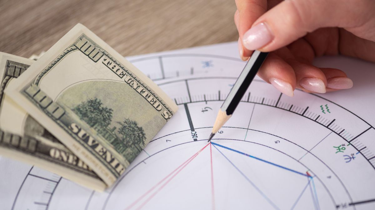 Cropped,View,Of,Astrologer,Drawing,Natal,Chart,Beside,Dollar,Banknotes