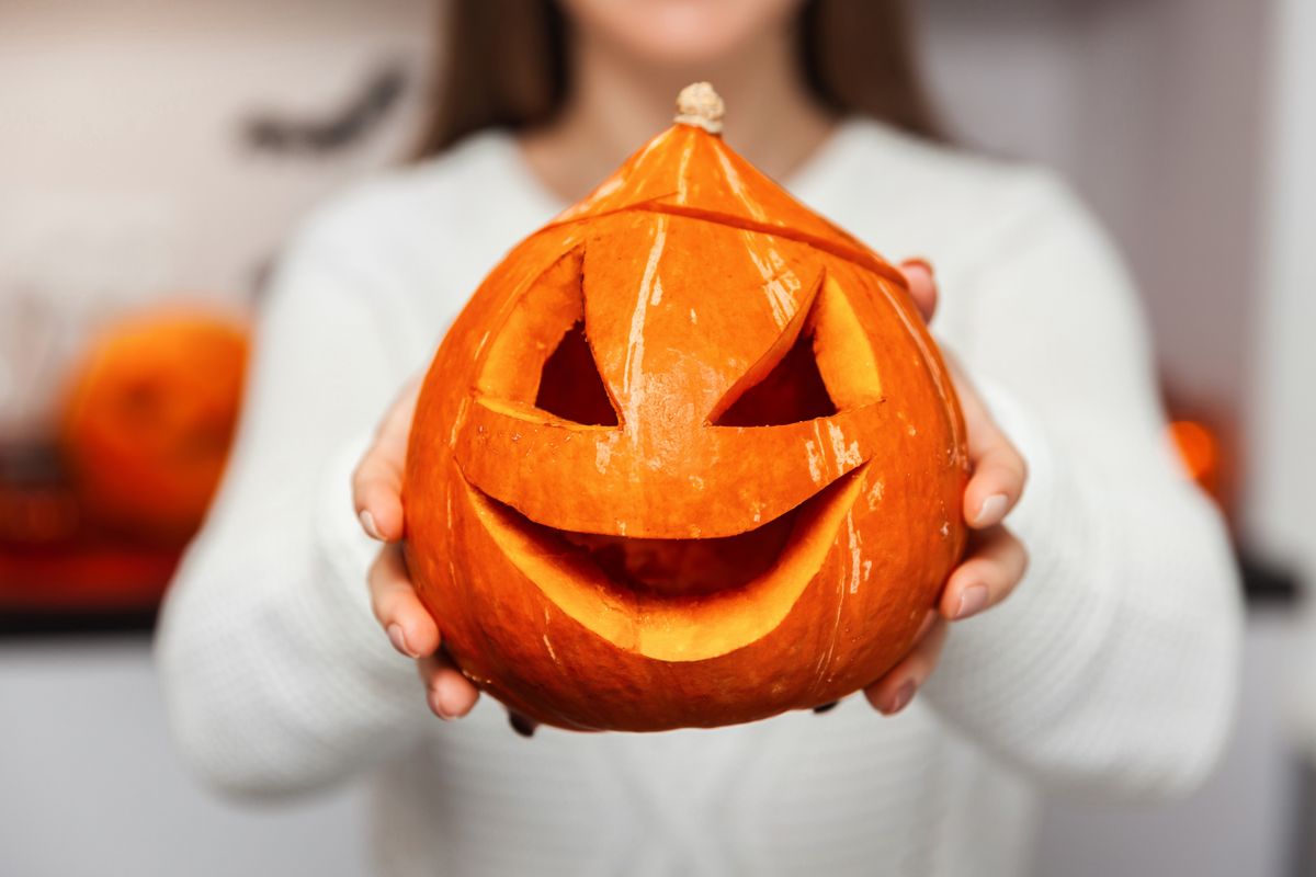 Holidays,,Halloween,,Woman,Holding,A,Pumpkin,On,Her,Outstretched,Hands,