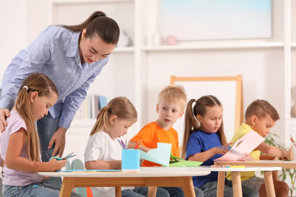 Nursery,Teacher,With,Group,Of,Cute,Little,Children,Drawing,And