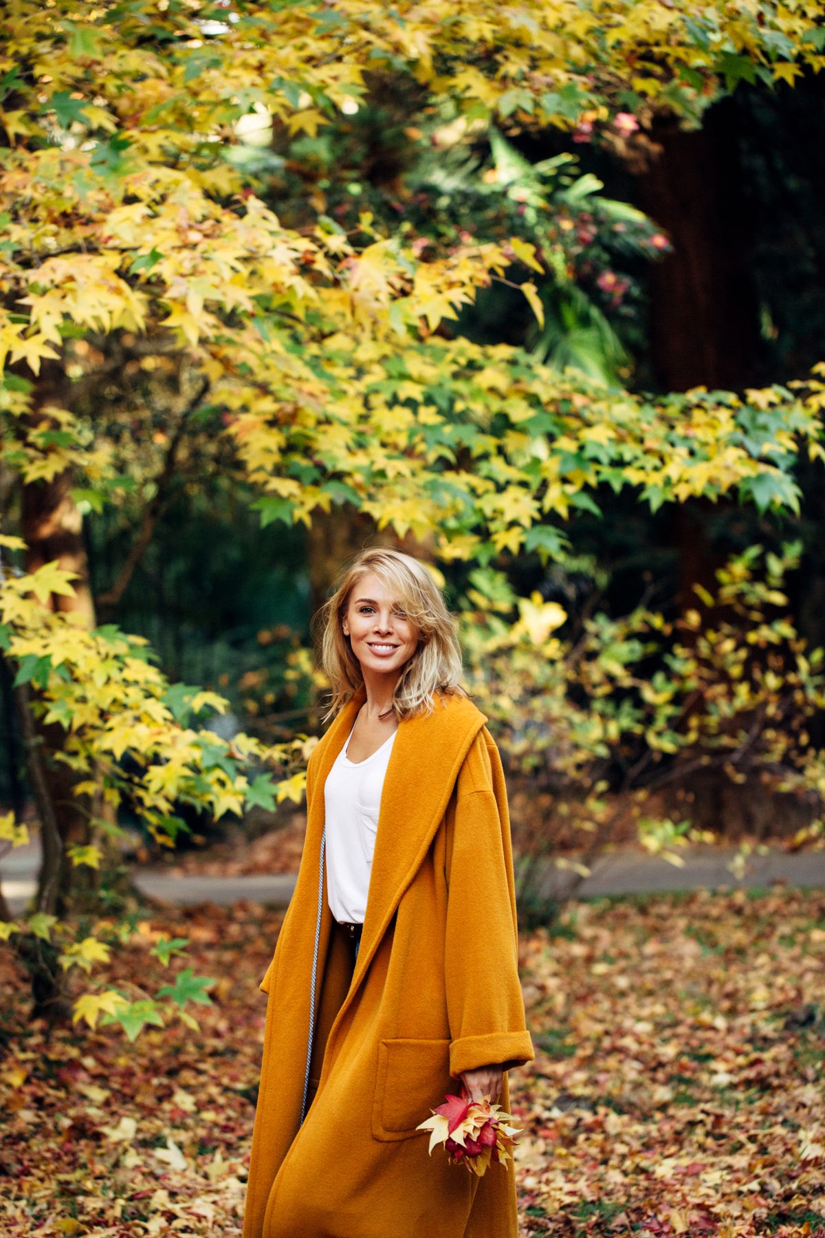 Beautiful Fashion Model wearin Coat in Autumn Park