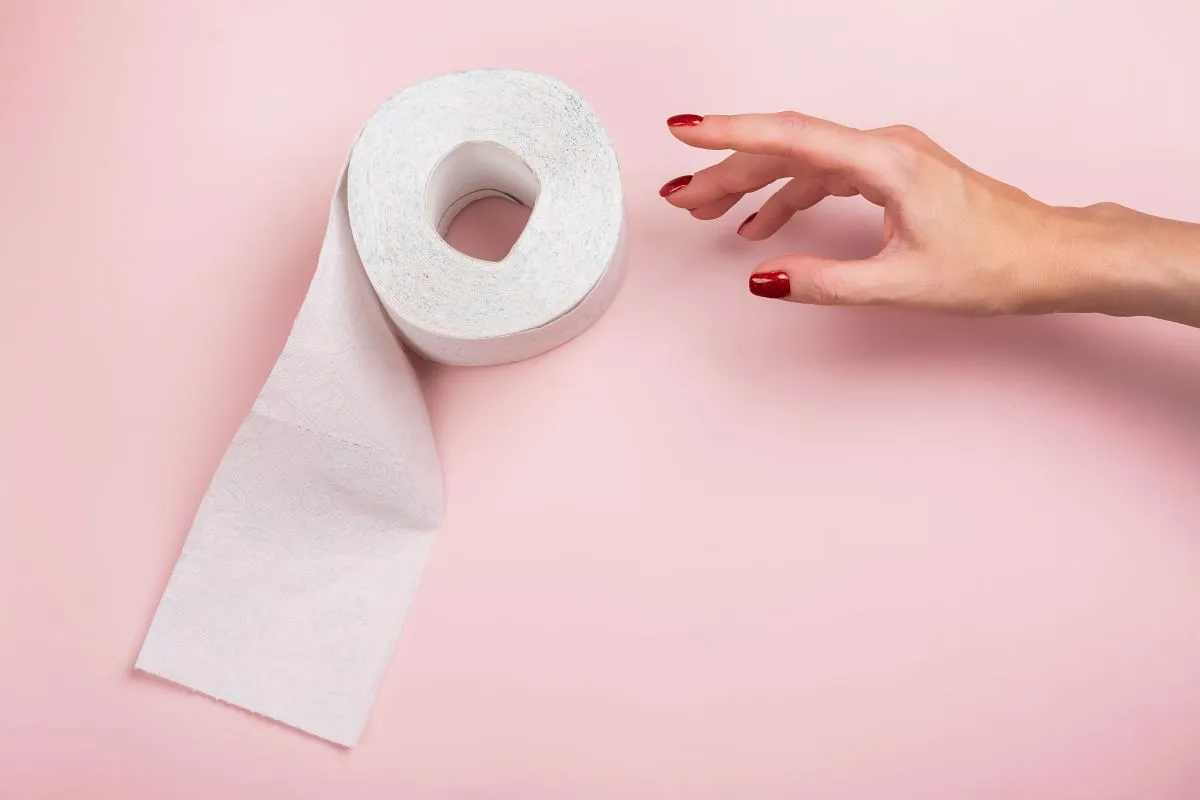 vécépapírral Roll,Of,Toilet,Paper,And,Woman's,Hand,On,Pink,Background.