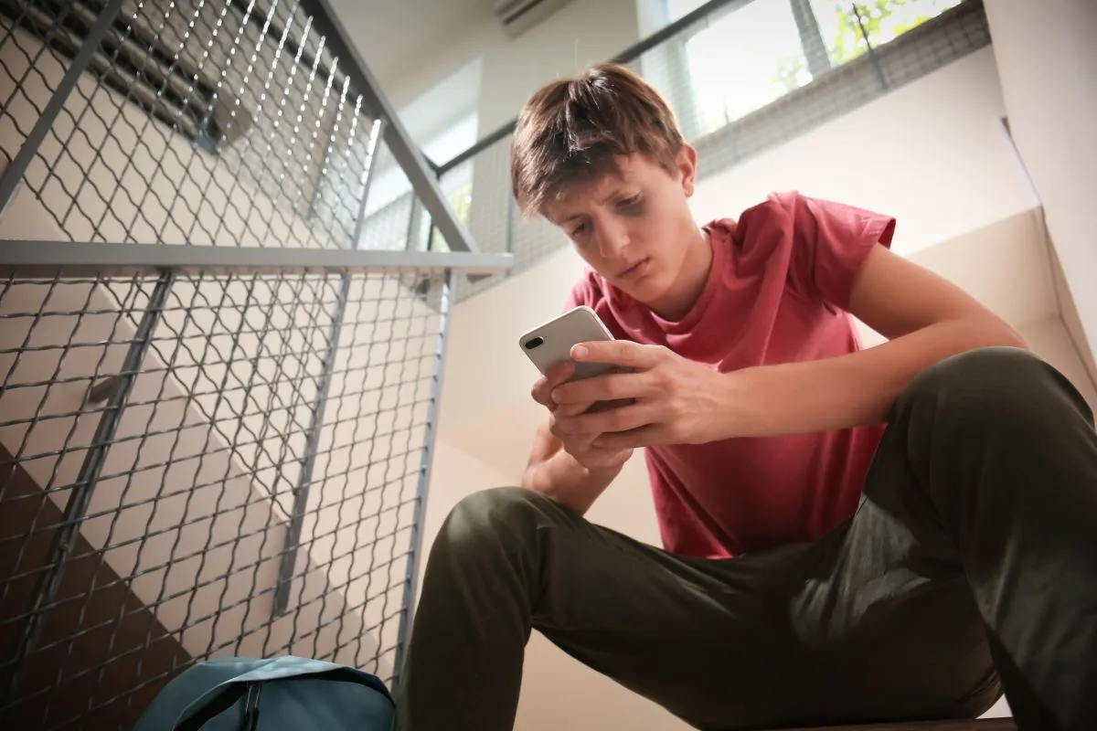 Sad,Teenage,Boy,With,Mobile,Phone,Sitting,On,Stairs.,Bullying