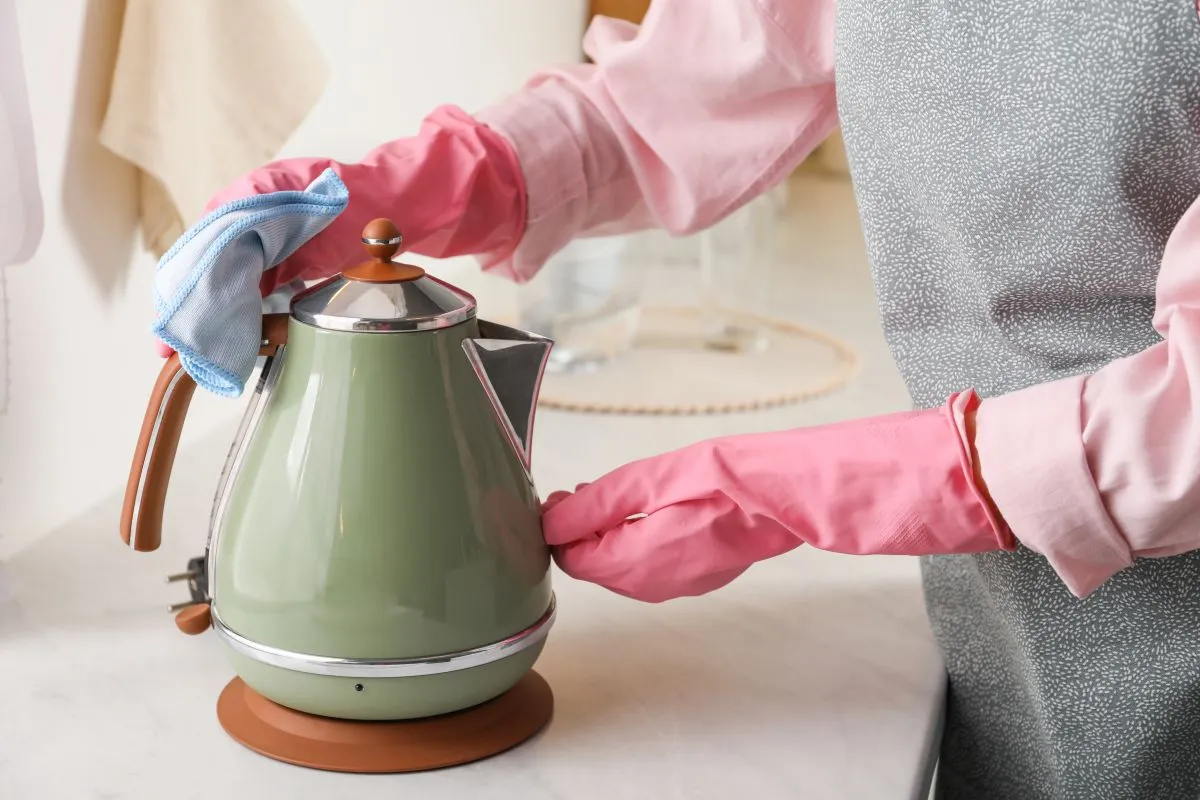 Woman,Wiping,Kettle,With,Rag,At,Countertop,In,Kitchen,,Closeup