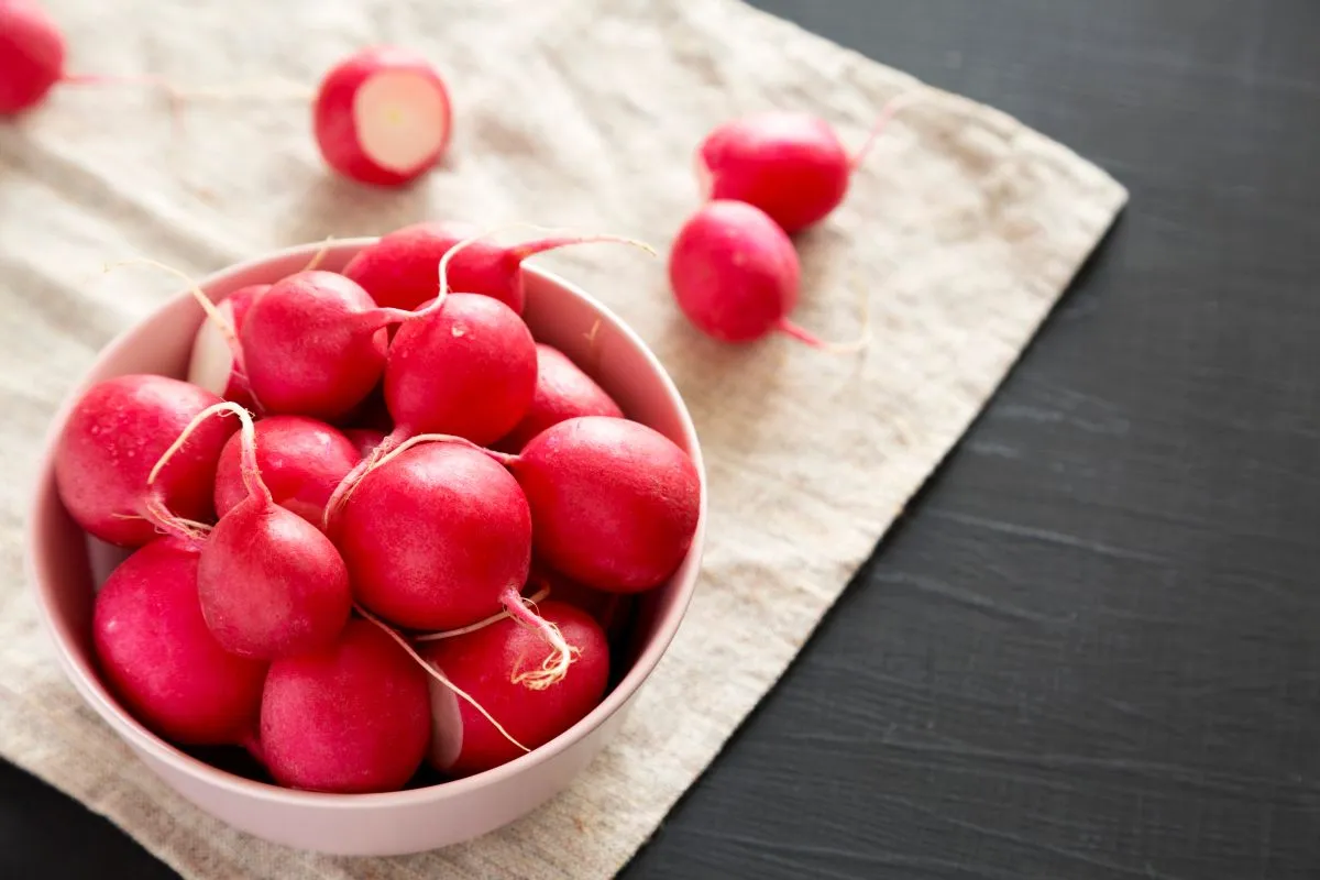 Roppantott retekFresh,Red,Radishes,In,A,Pink,Bowl,Over,Black,Surface,