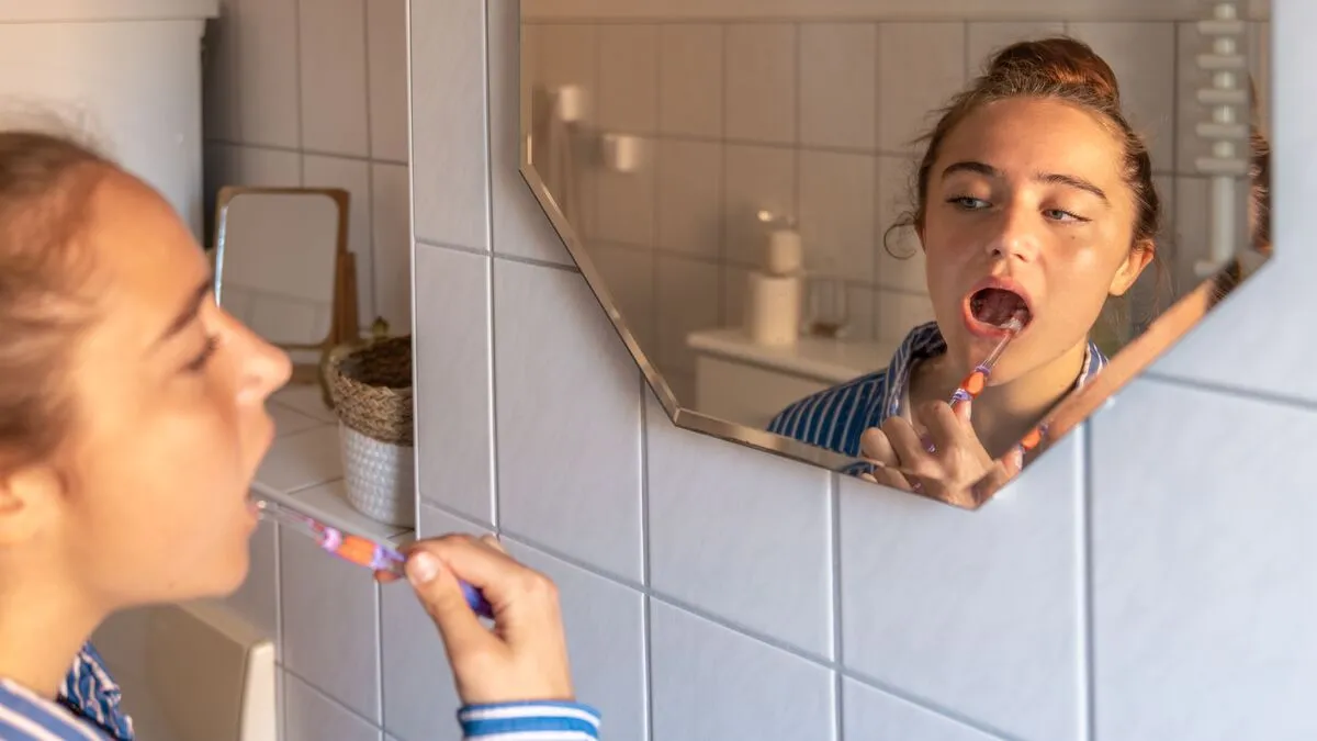 Teenage girl brushing her teeth. Girl brushing her teeth in front of the mirror in the bathroom.