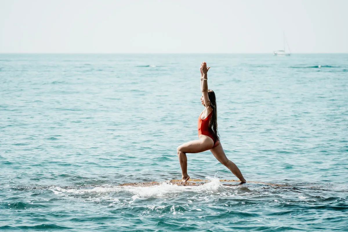 Woman sea yoga. Back view of free calm happy satisfied woman with long hair standing on top rock with yoga position against of sky by the sea. Healthy lifestyle outdoors in nature, fitness concept