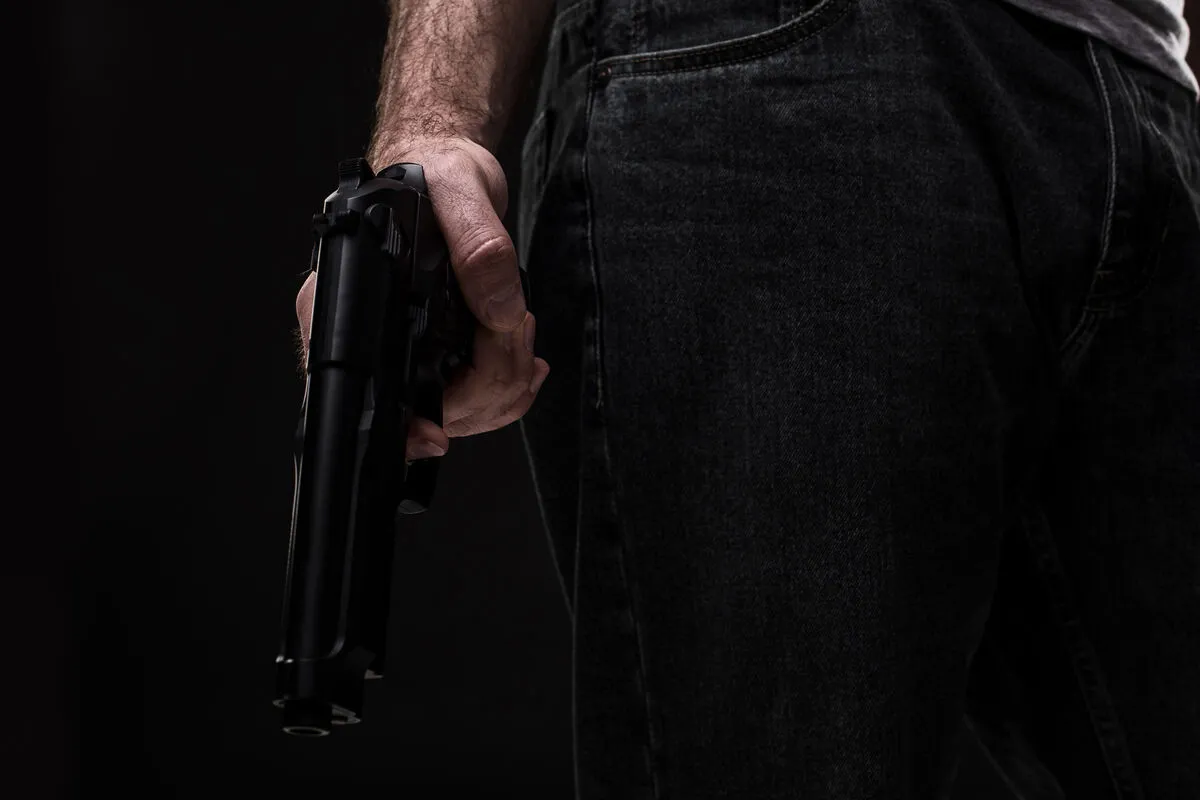 Killer with gun on black background at the studio