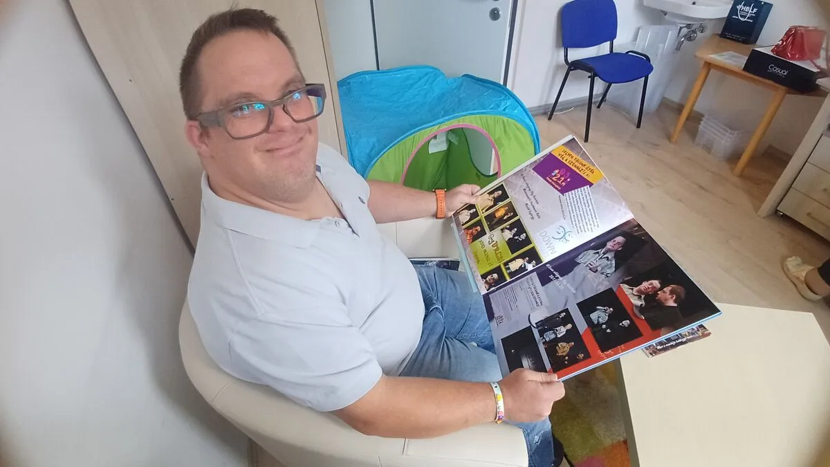 A Down-szindrómával élő György a 30. születésnapjára a Csodavár által készített könyvet lapozgatja