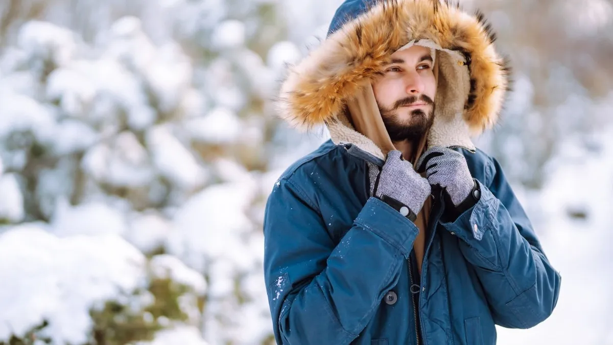 Portrait of young man in snowy winter forest. Season, christmas, travel and people concept.