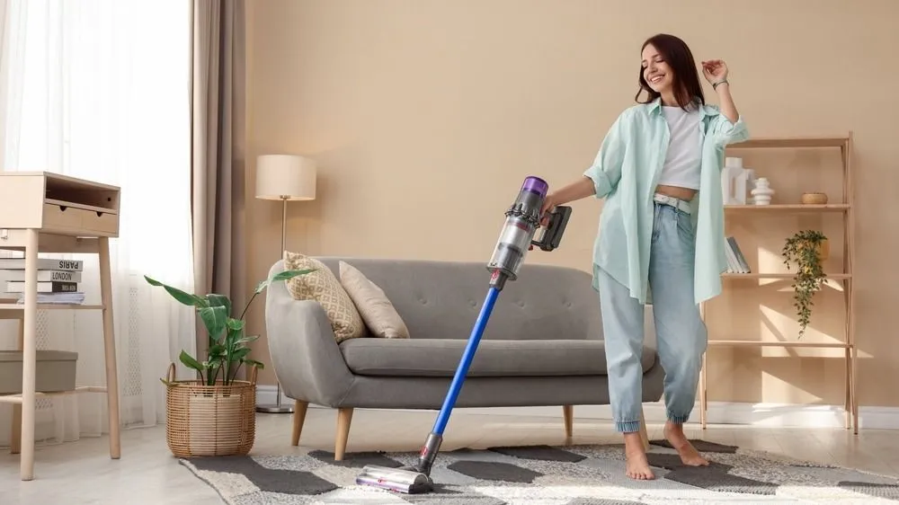 Smiling,Young,Woman,Cleaning,Rug,With,Cordless,Vacuum,Cleaner,In