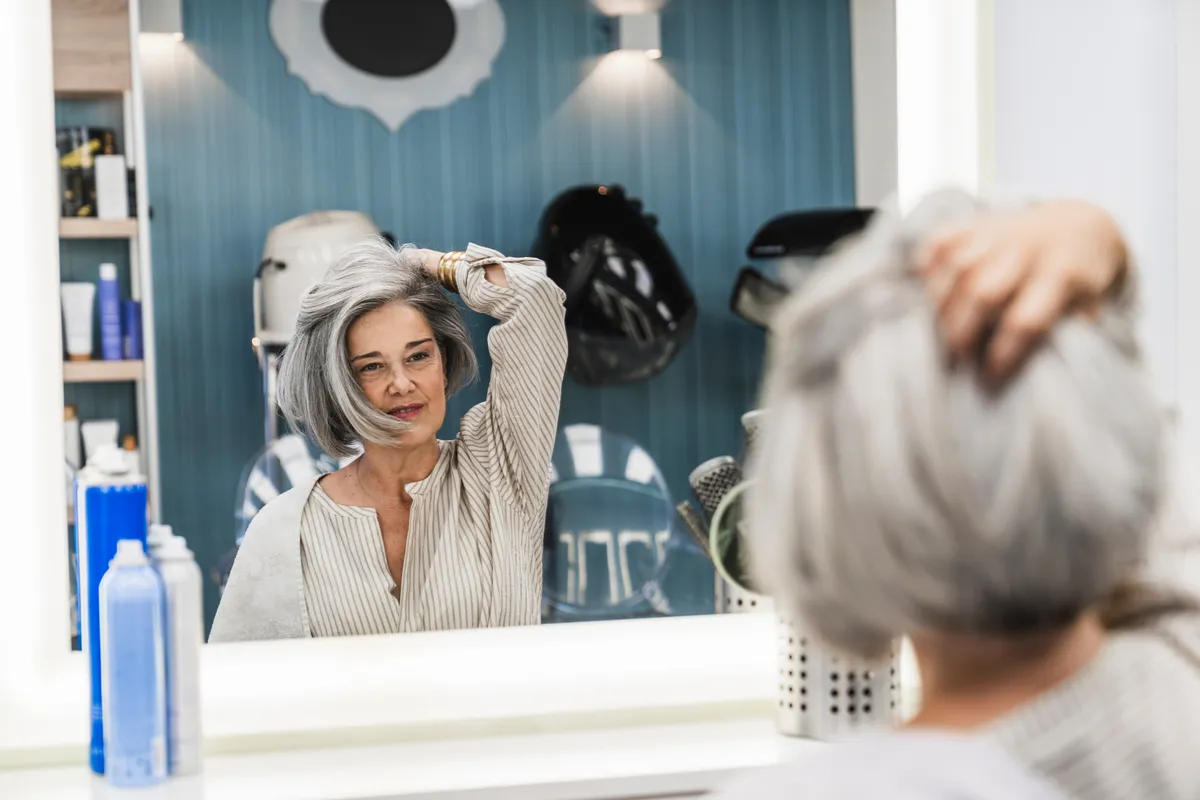 Divat az ősz haj, Senior,Woman,Looking,At,Reflection,In,Salon,Mirror,,Touching,Her