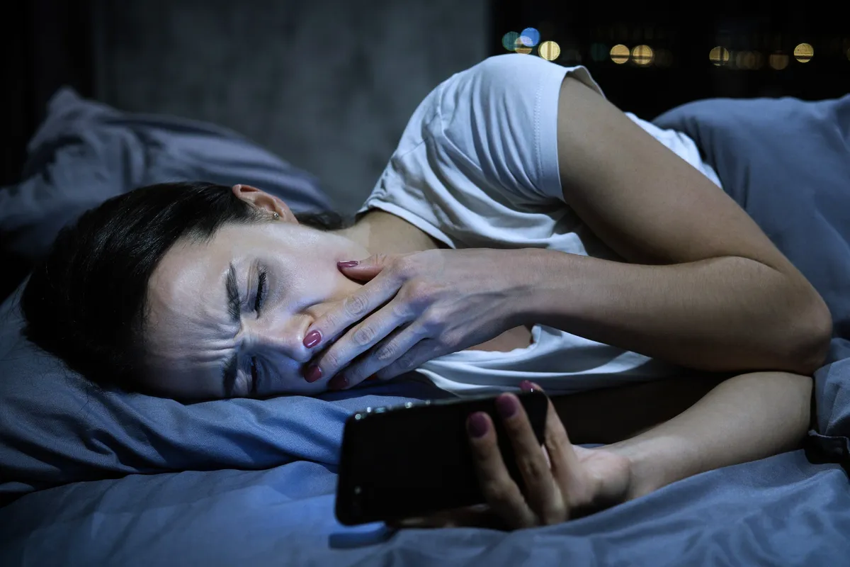 5 tárgy, amit soha ne tegyél az ágy melléYoung,Yawning,Tired,Female,Using,Mobile,Phone,In,Bed,,Closing
