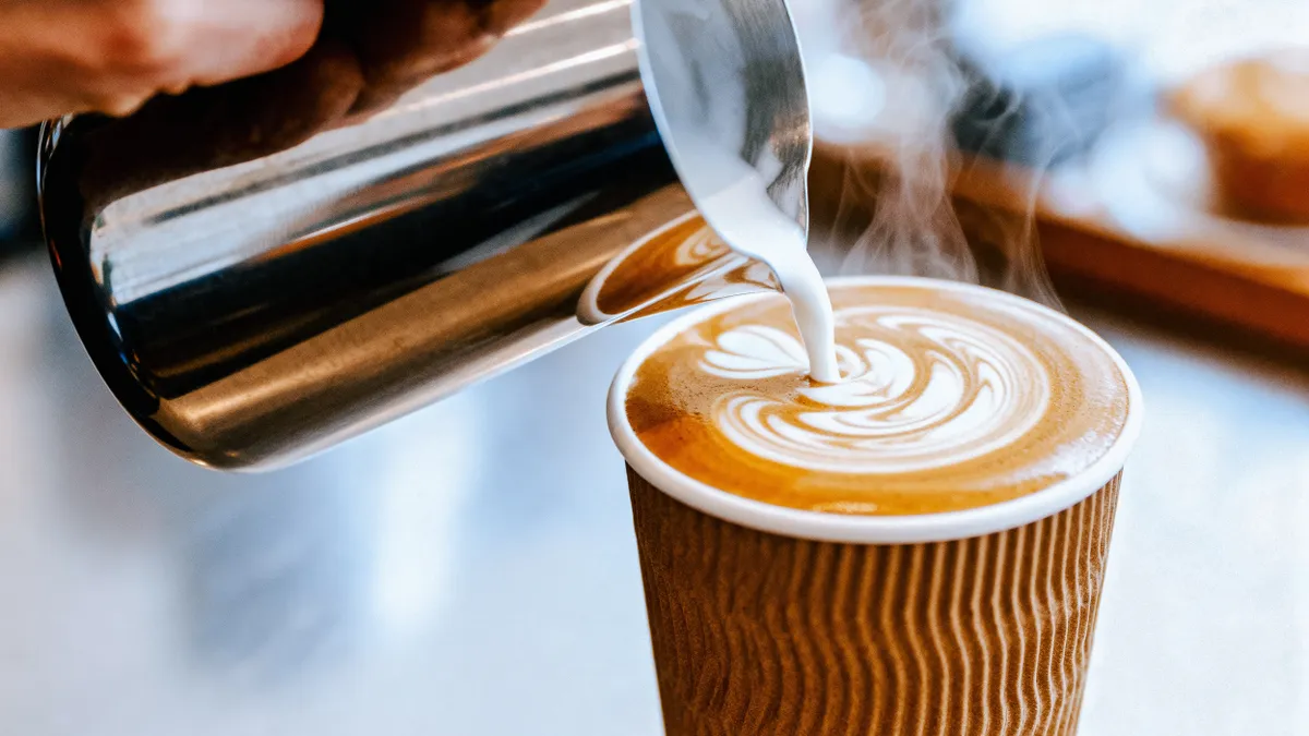Kávé tejjel A,Barista,Pouring,Steamed,Milk,Into,A,Brown,Paper,Coffee