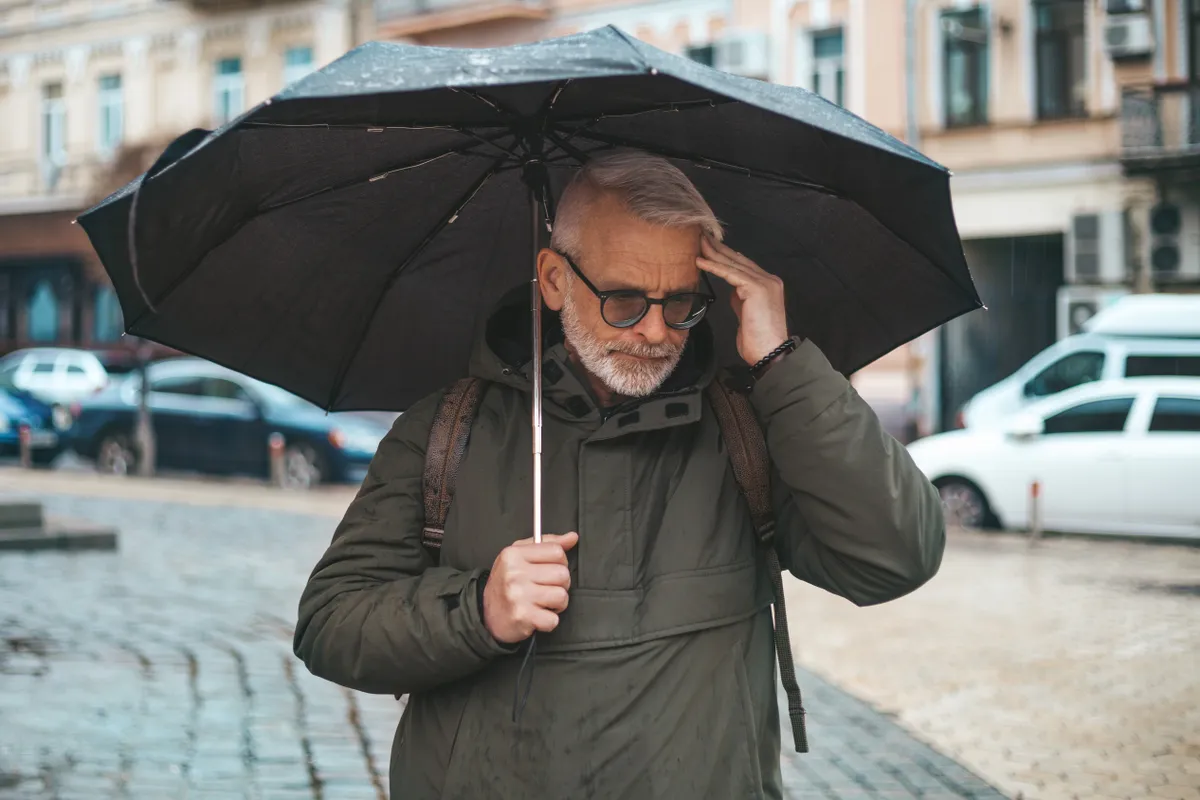 Mature,Man,With,Migraine,In,Rainy,Weather,Under,An,Umbrella.