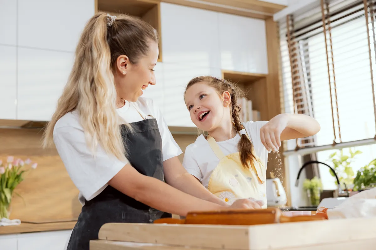 Tészta trükkYoung,Beautiful,Daughter,Sprinkling,Dough,With,Flour,Talking,Smiling.,Mother