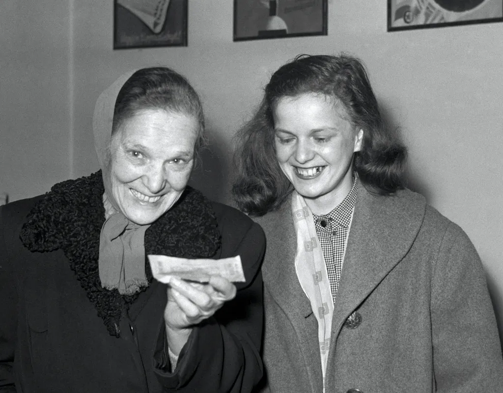 Retró lottó nyertesek
Ring Mária; Ring Sándorné

Budapest, 1957. április 12.

Özv. Ring Sándorné nyugdíjas hatgyerekes családanya, az első öttalálatos lottónyeremény boldog tulajdonosa kezében az 1.758.466-os számú szelvénnyel, mellyel négy gyermeke és sa