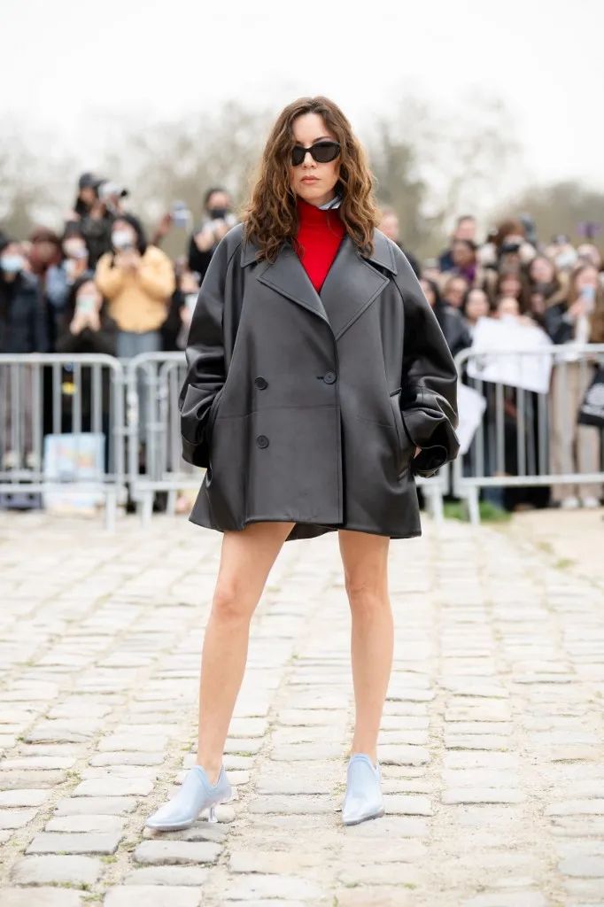 Aubrey Plaza a Loewe bemutatón egy túlméretezett bőrdzsekit viselt, piros pulóverrel és bokacsizmával párosítva.